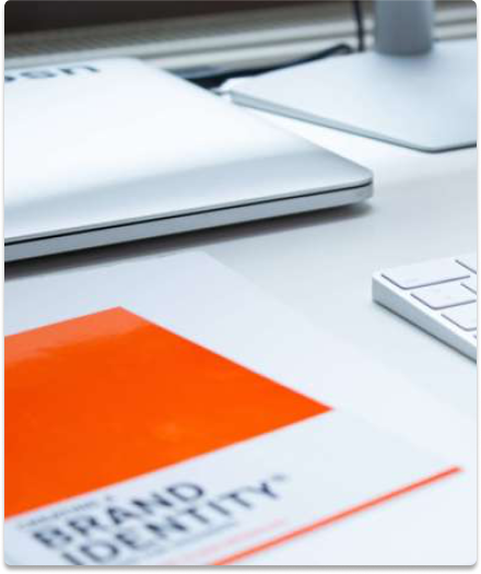 laptop, keyboard in background with brand design book in foreground